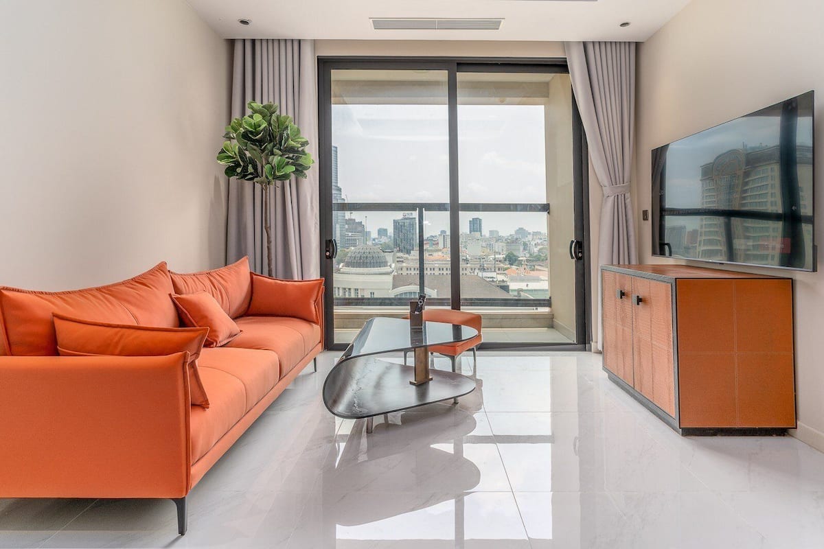 A modern living room with a sofa, a glass table, and a TV.
