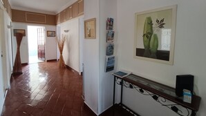 A hallway with a tiled floor, a wall-mounted console table with a speaker, and framed artwork. - Apartment in villa with private pool and garden, 3 bedrooms, warm welcome.  (ANTIBES)