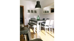A dining area with a table and chairs, a hanging light fixture, and framed pictures on the wall. - MODERN APARTMENT IN THE CENTER (Vilanova i la Geltrú)