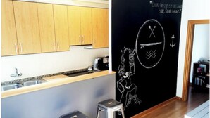 A kitchen with wooden cabinets, a blackboard with drawings, and two metal stools. - MODERN APARTMENT IN THE CENTER (Vilanova i la Geltrú)