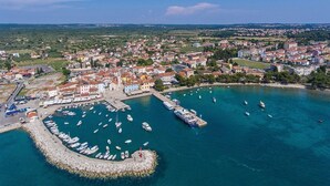An aerial view of a coastal town with a marina, boats, and buildings. - Apartment Dana (Fazana)