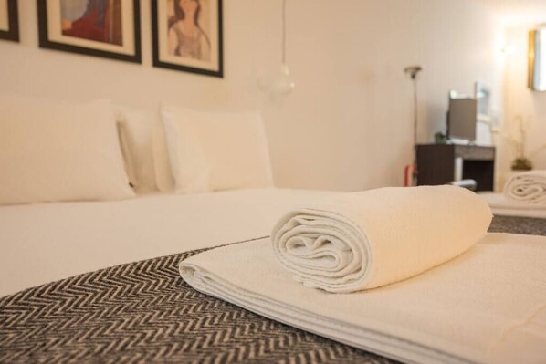 A neatly made bed with a folded white towel and a patterned bedspread.