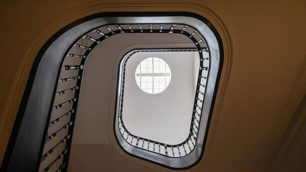 A spiral staircase with a circular window at the top, surrounded by a metal railing. - TOUCHY PORTO - Charming apartment located at Praça da Republica (Porto)