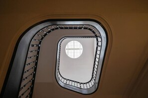Una scala a chiocciola con una finestra circolare sulla sommità, circondata da una ringhiera metallica.