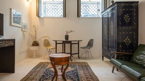 A living room with a sofa, a small round table, two chairs, a cabinet, and a TV. - TOUCHY PORTO - Charming apartment located at Praça da Republica (Porto)