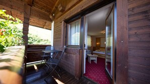 Eine Holzhütte mit Balkon, einem kleinen Tisch und einem Bett mit rotem Teppich.