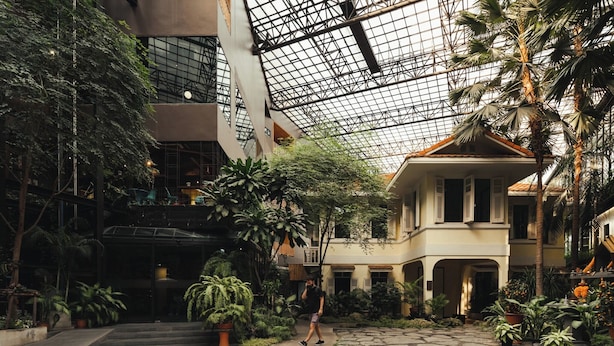 An indoor courtyard with a glass ceiling, stone pathways, and lush greenery. - 515 VICTORY Hotel (Bangkok)