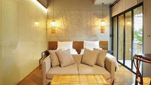 A modern hotel room with a sofa bed, a small table, and a decorative wall with geometric patterns. - 515 VICTORY Hotel (Bangkok)