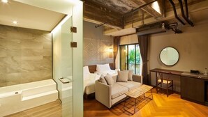A modern hotel room with a bathtub, a sofa, a dining table, and a large mirror. - 515 VICTORY Hotel (Bangkok)