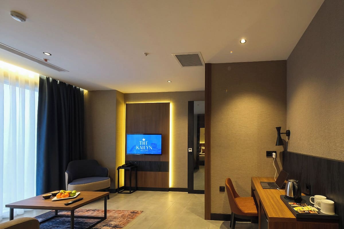 Una habitación de hotel moderna con una televisión de pantalla plana, un sofá, una mesa de comedor y una zona de café.