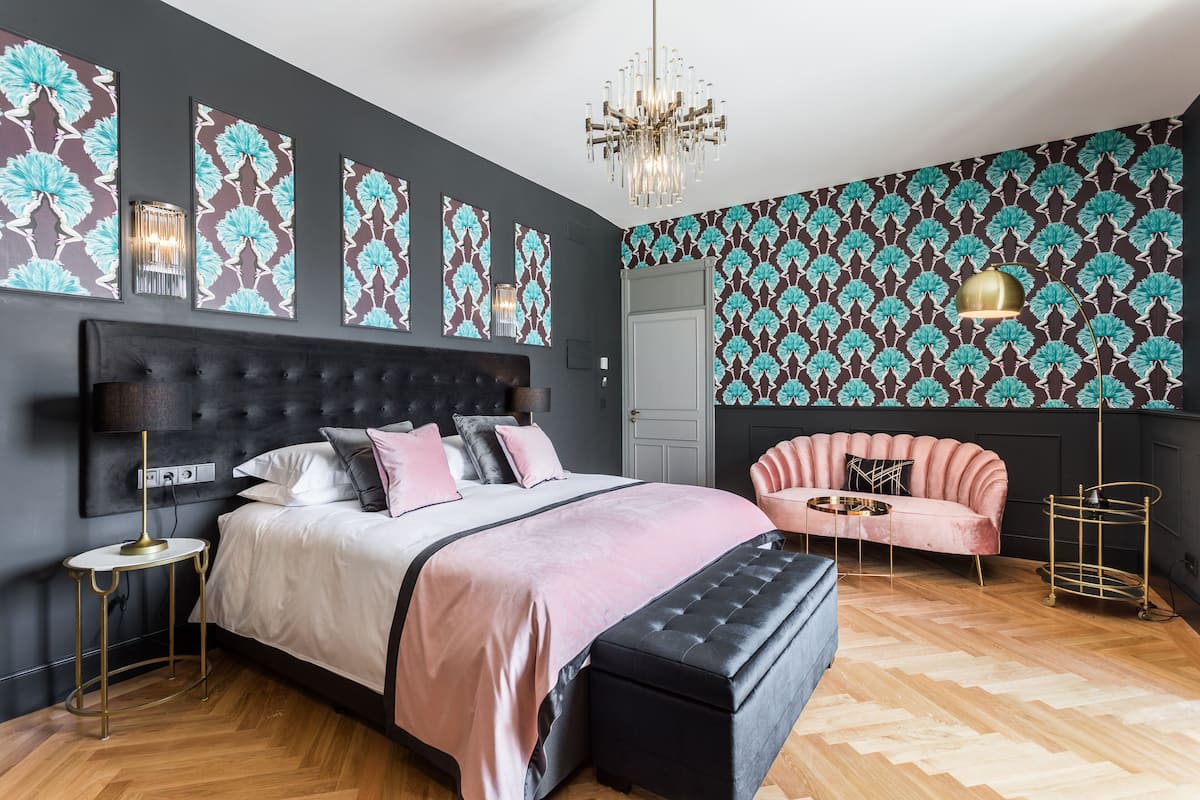 Un dormitorio moderno con una cama grande, una chaise longue y una araña.
