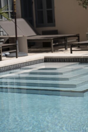 A swimming pool with steps leading into it, surrounded by outdoor seating and a building in the background. - Ten Mallorca - Adults Only (Sineu)