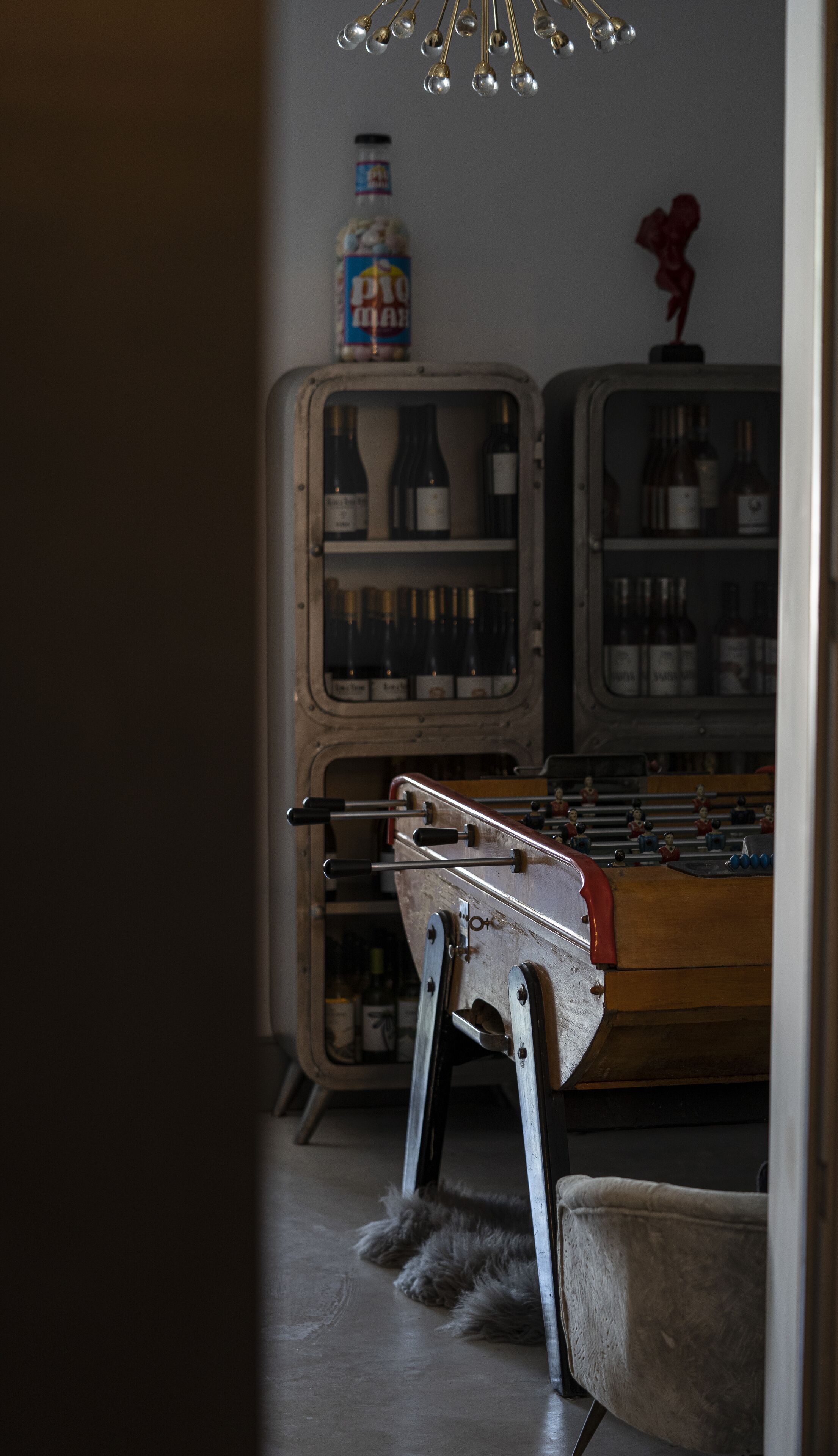 Habitación de estilo antiguo con una mesa de madera, una radio antigua y una colección de botellas en estantes.
