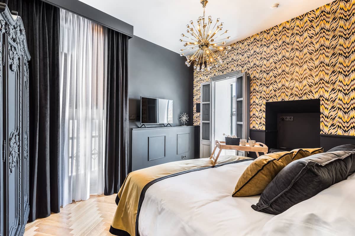 Una habitación de hotel moderna con una cama grande, televisor, armario y espejo.