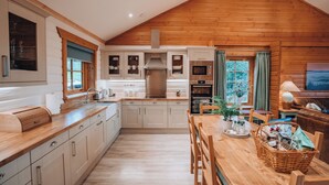 A modern kitchen with wooden cabinetry, a central island, and a dining area with a wooden table and chairs.