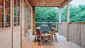 A wooden deck with a table and chairs, surrounded by wooden walls and a wooden railing.