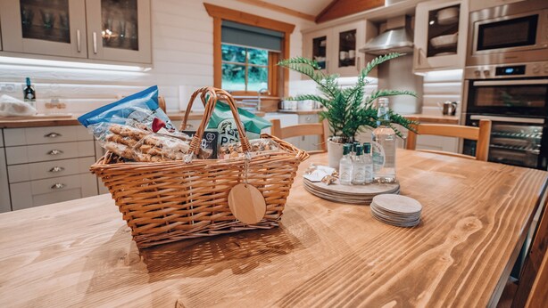 A kitchen with wooden cabinets, a dining table with a basket of bread, and a potted plant.