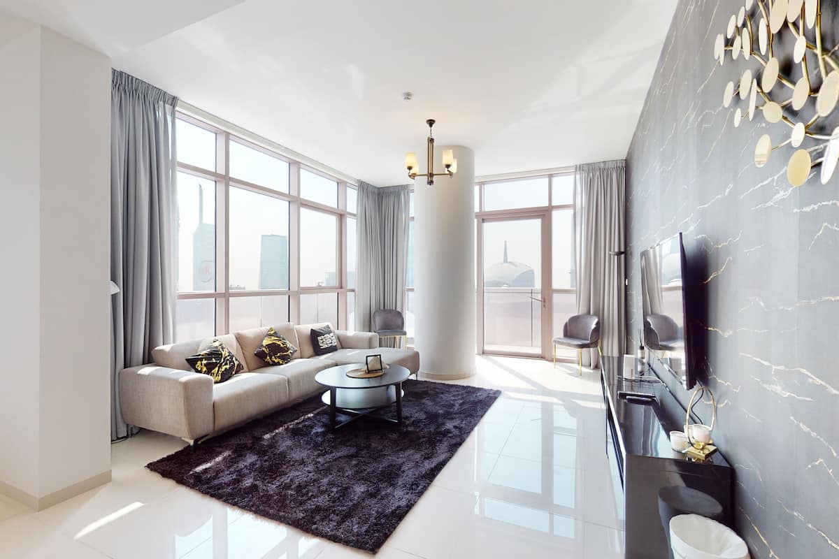 A modern living room with a sofa, coffee table, and a large window with curtains.