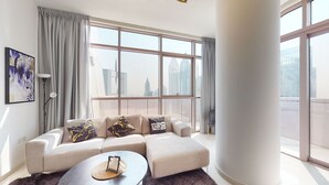 Un salón moderno con un sofá, una mesa de centro y un amplio ventanal con vista a la ciudad.