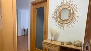 A hallway with a wooden door, a wall-mounted mirror, and a small wooden desk with decorative items.