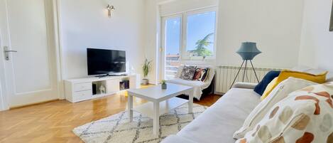Un salon moderne avec un téléviseur à écran plat, un canapé blanc et une table basse.