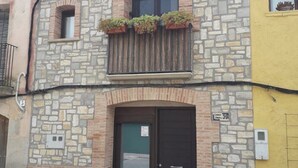 En toetagers steng bygning med en sort dør og en lille balkon med blomsterkrukker.