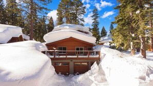 Une cabane en bois dotée d’un balcon, entourée d’arbres couverts de neige.