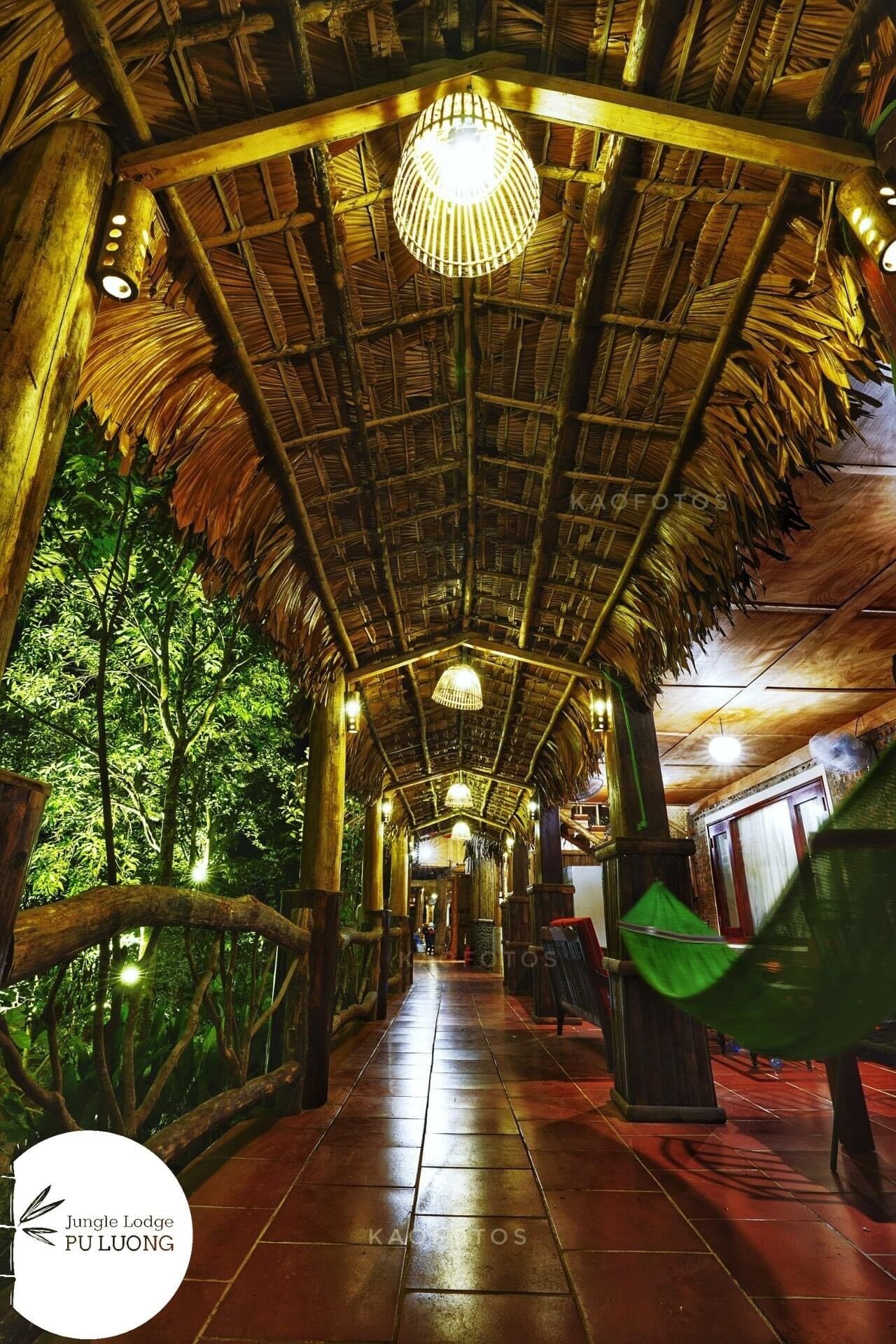 Une allée couverte, dotée d’un toit de chaume, de piliers en bois et de lampes suspendues.