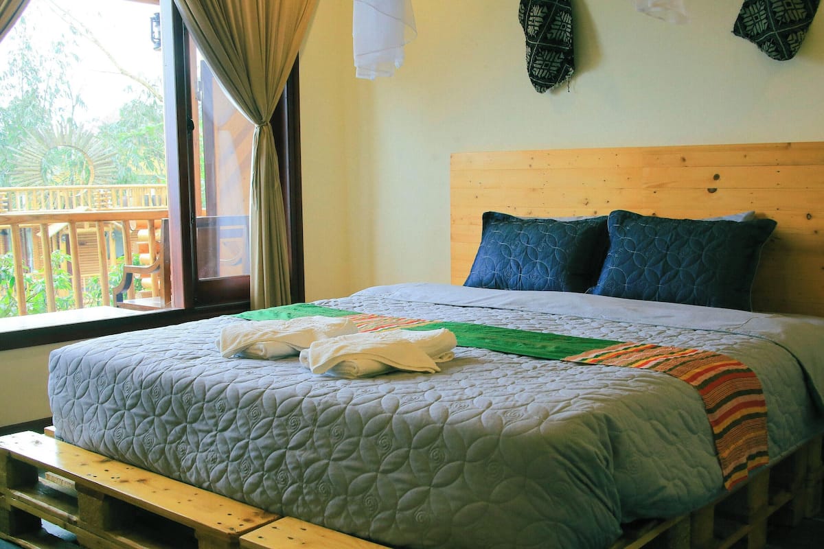 A bed with a quilted cover, a wooden headboard, and pillows.