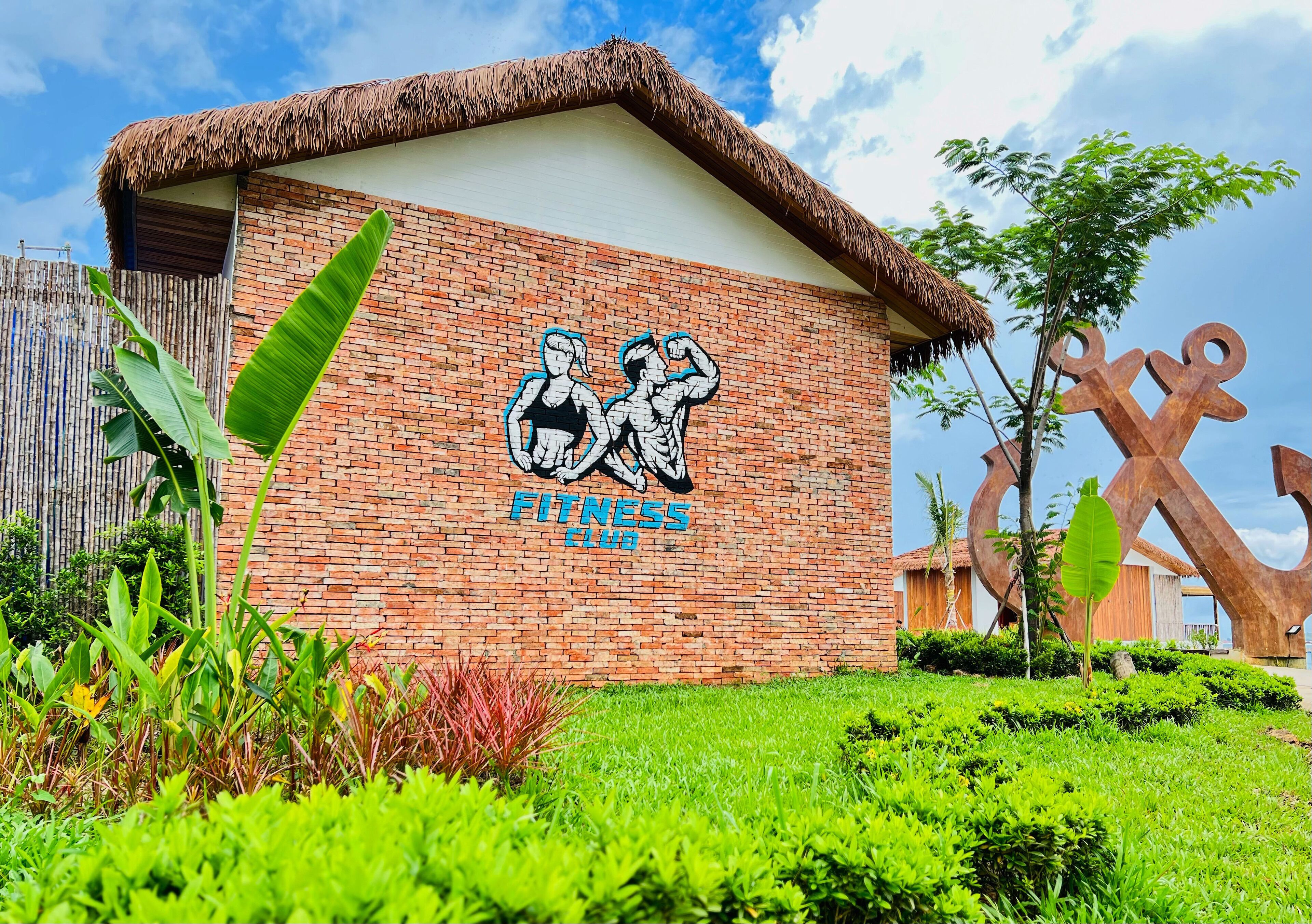 A brick building with a thatched roof and a sign reading "Fitness Club".
