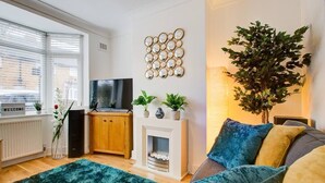 A modern living room with a fireplace, a television, and a large green rug.