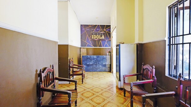 A hallway with wooden chairs, a reception desk, and a patterned floor.