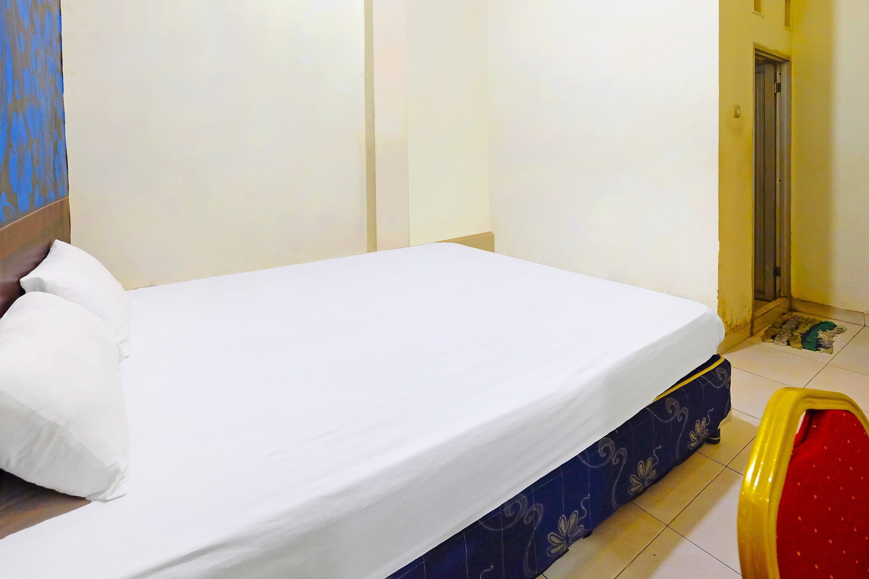 Una habitación de hotel con una cama individual, un sofá azul estampado y una silla roja.