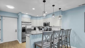 A modern kitchen with white cabinets, stainless steel appliances, and a central island with bar stools.