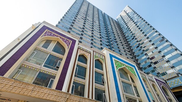 A tall building with multiple floors and a mix of architectural styles, including traditional and modern elements. - OYO 3691 Apartment Saladin Mansion (Depok)