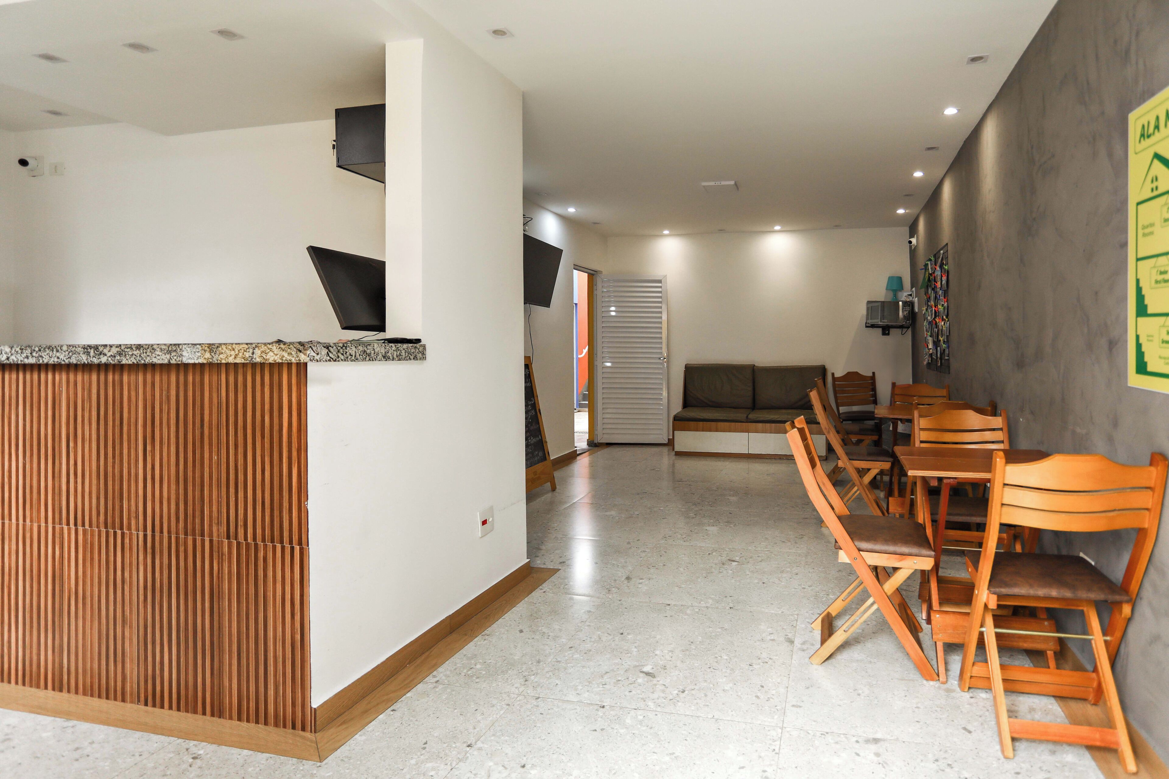 Un vestíbulo de hotel con mostrador de recepción, zona de estar y televisión montada en la pared.