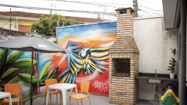 Un patio al aire libre con un mural, un horno de ladrillo y asientos.
