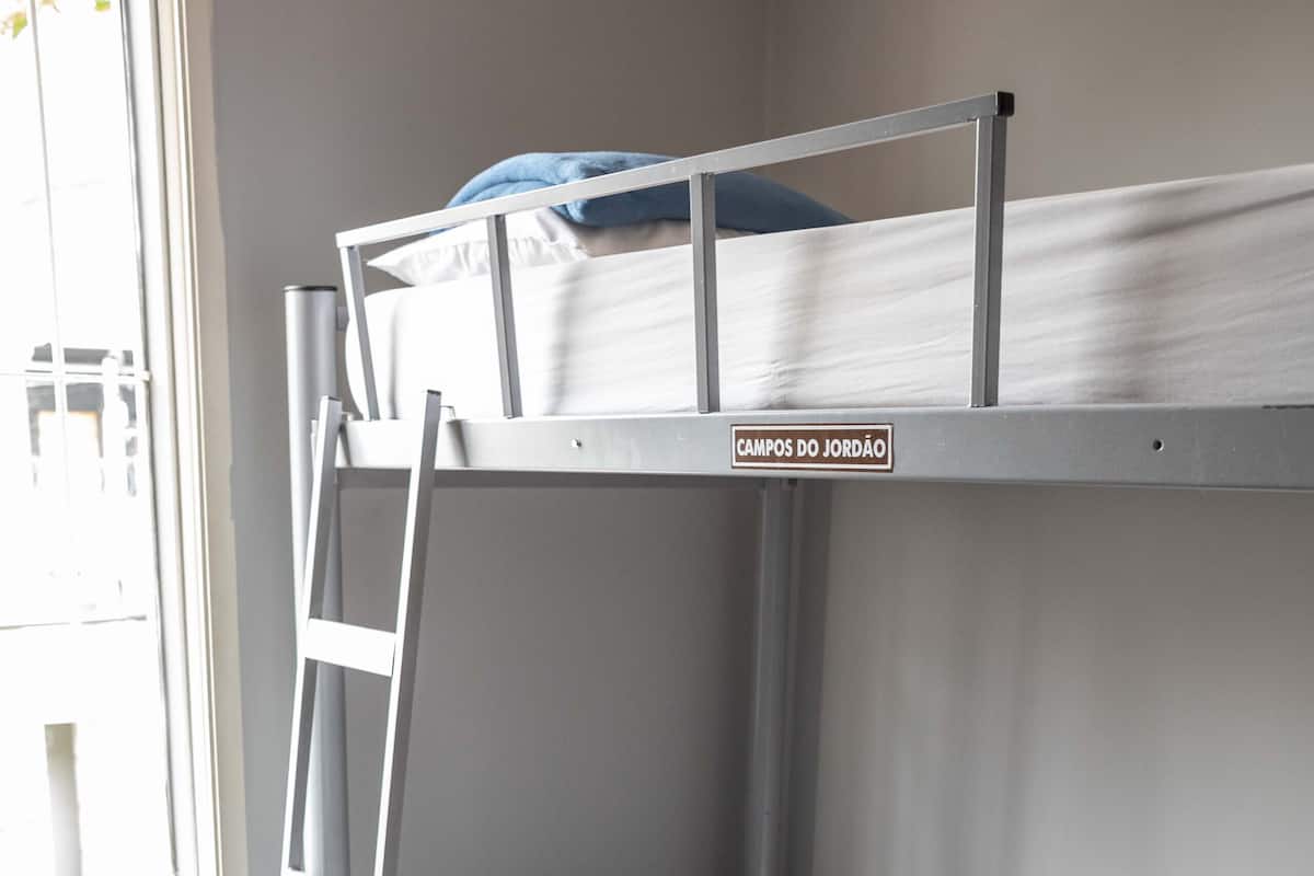 Un letto a castello con una scala, una finestra con tende e un pavimento in legno.