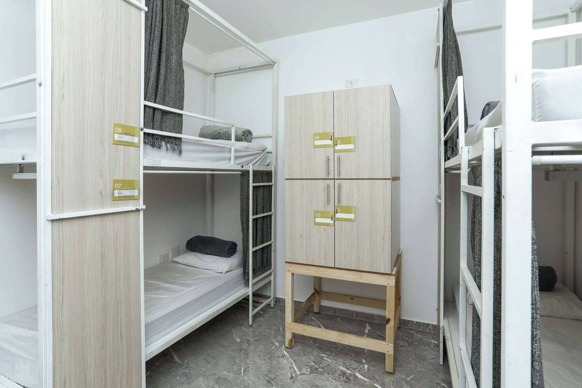 Una camera del dormitorio con letti a castello, un'armadio e un piccolo tavolo.