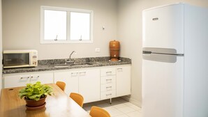Una cocina equipada con microondas, pileta, mostrador, alacenas y refrigerador.