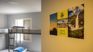 Habitación con literas, una escalera, una ventana con persianas y una pared decorada con un collage enmarcado de fotografías y texto de viajes.