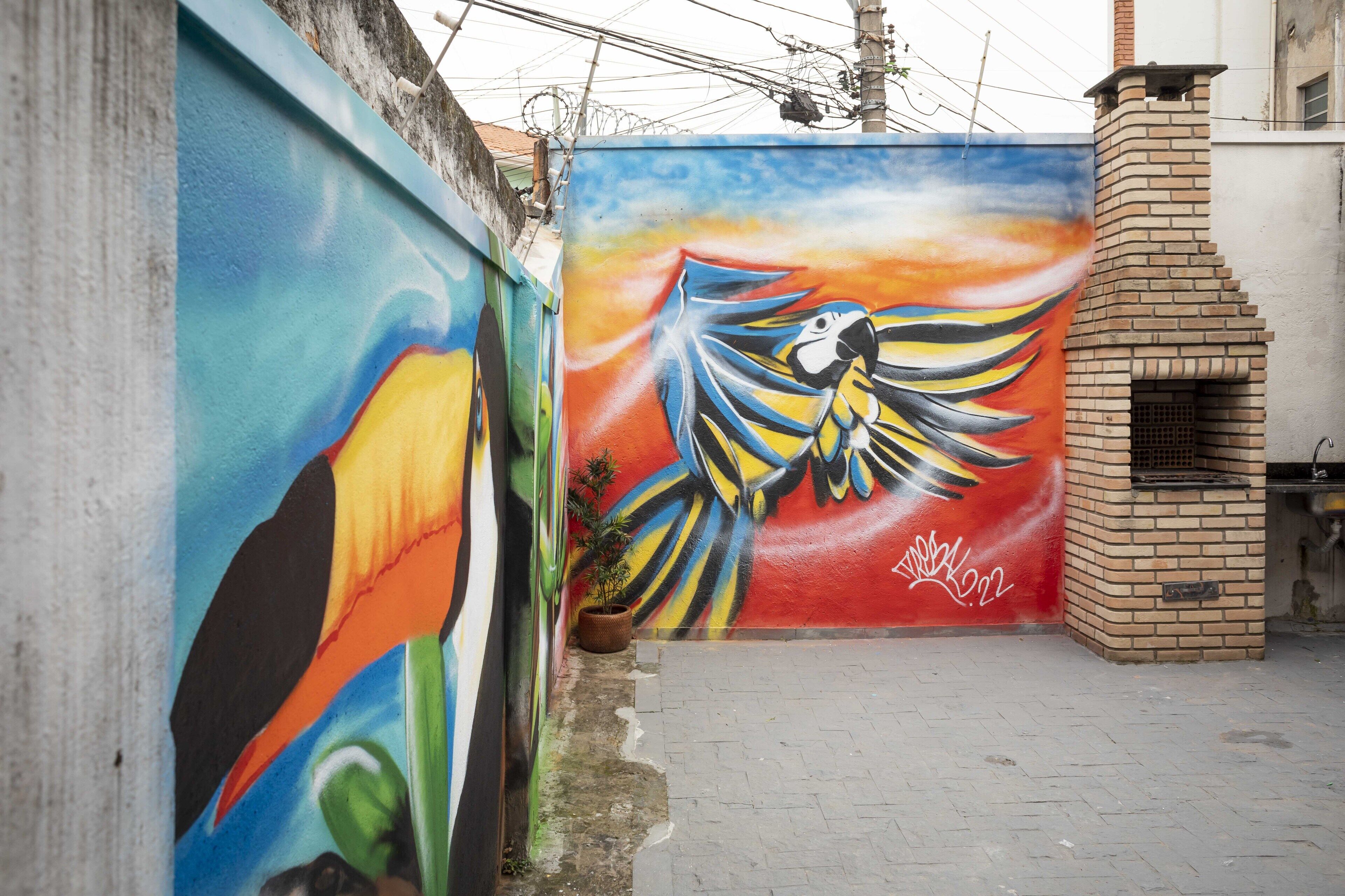 A mural of a bird on a wall, a brick oven, and a potted plant.