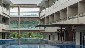 A multi-level hotel with a central swimming pool, balconies, and a view of greenery. - Canyon Hotels & Resorts Boracay (Boracay Island)