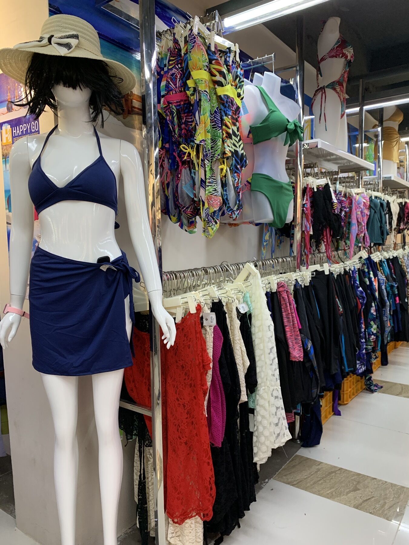 Una tienda de ropa con un maniquí vestido con un traje de baño azul y un sombrero.
