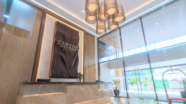 A reception area with a modern design, featuring a reception desk, a large glass window, and a ceiling with recessed lighting. - Canyon Hotels & Resorts Boracay (Boracay Island)