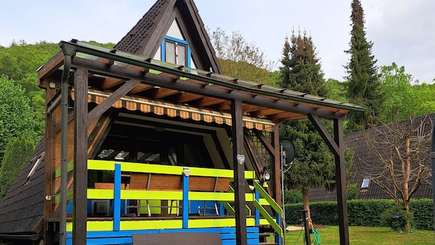 Una cabaña de madera con un exterior colorido, un jacuzzi y un patio cubierto de césped.
