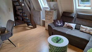 Una sala de estar moderna con una escalera, un sofá, una mesa de centro y vistas al exterior.