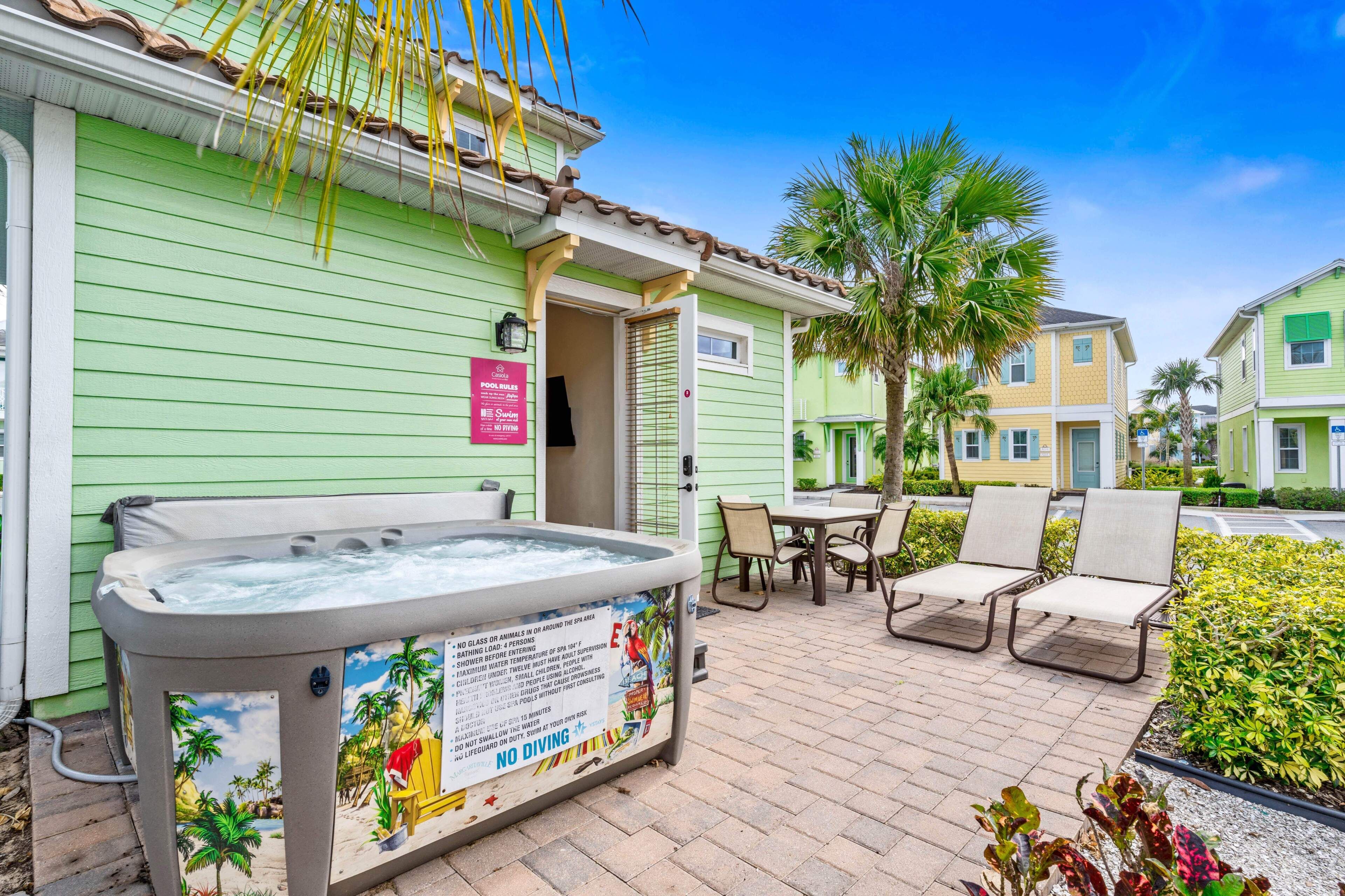 A spa area with a hot tub, outdoor seating, and a poolside sign with rules.