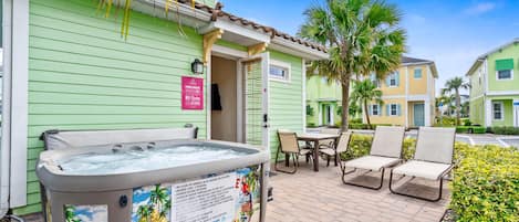 A spa area with a hot tub, outdoor seating, and a poolside sign with rules.