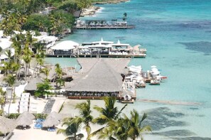 A resort with overwater bungalows, a pier, and a beach area. - Hotel boca del mar playa boca chica  (Boca Chica)